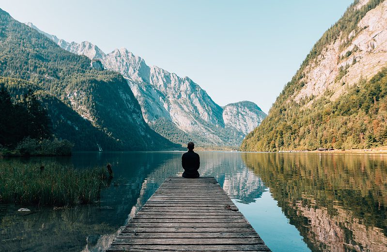 a person sitting on wooden planks across the lake scenery